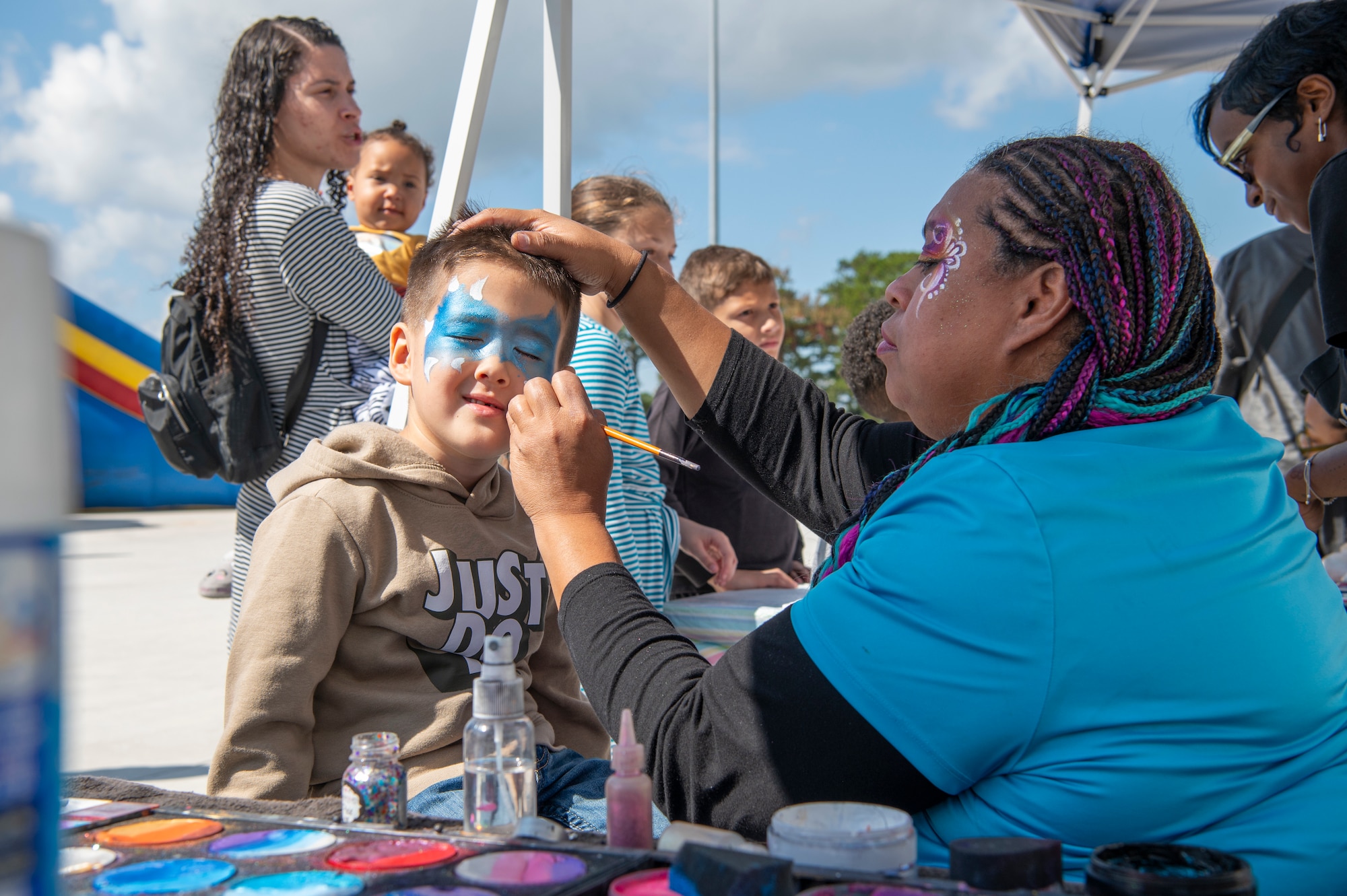 a child gets his face painted by a woman