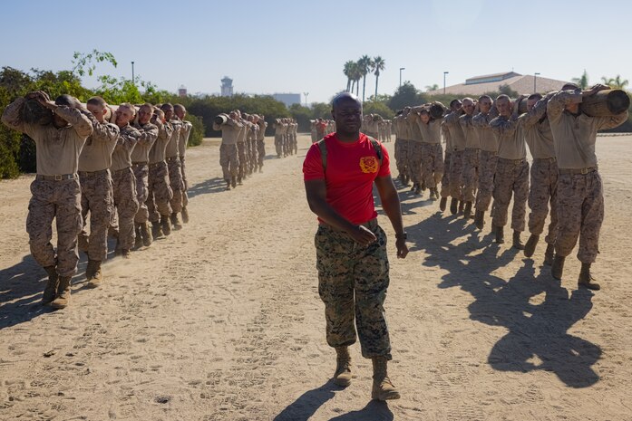U.S. Marine Corps Staff Sgt. Dexton Plummer, a drill instructor with Charlie Company, 1st Recruit Training Battalion, observes recruits during a log during a log drill exercise at Marine Corps Recruit Depot San Diego, Oct. 16, 2023. Recruits carried a 250-pound log, executing various exercises to strengthen their bodies, minds, and promote teamwork. SSgt. Plummer is from Fort Lauderdale, Fla. (U.S. Marine Corps photo by Lance Cpl. Jacob B. Hutchinson)