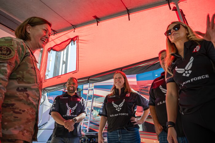 woman in uniform laughs with four individuals wearing Air Force shirts