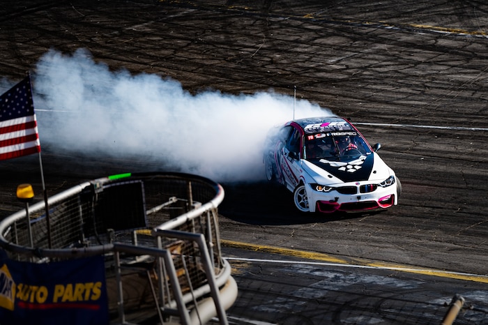 race car kicks up smoke as it makes the sharp turn