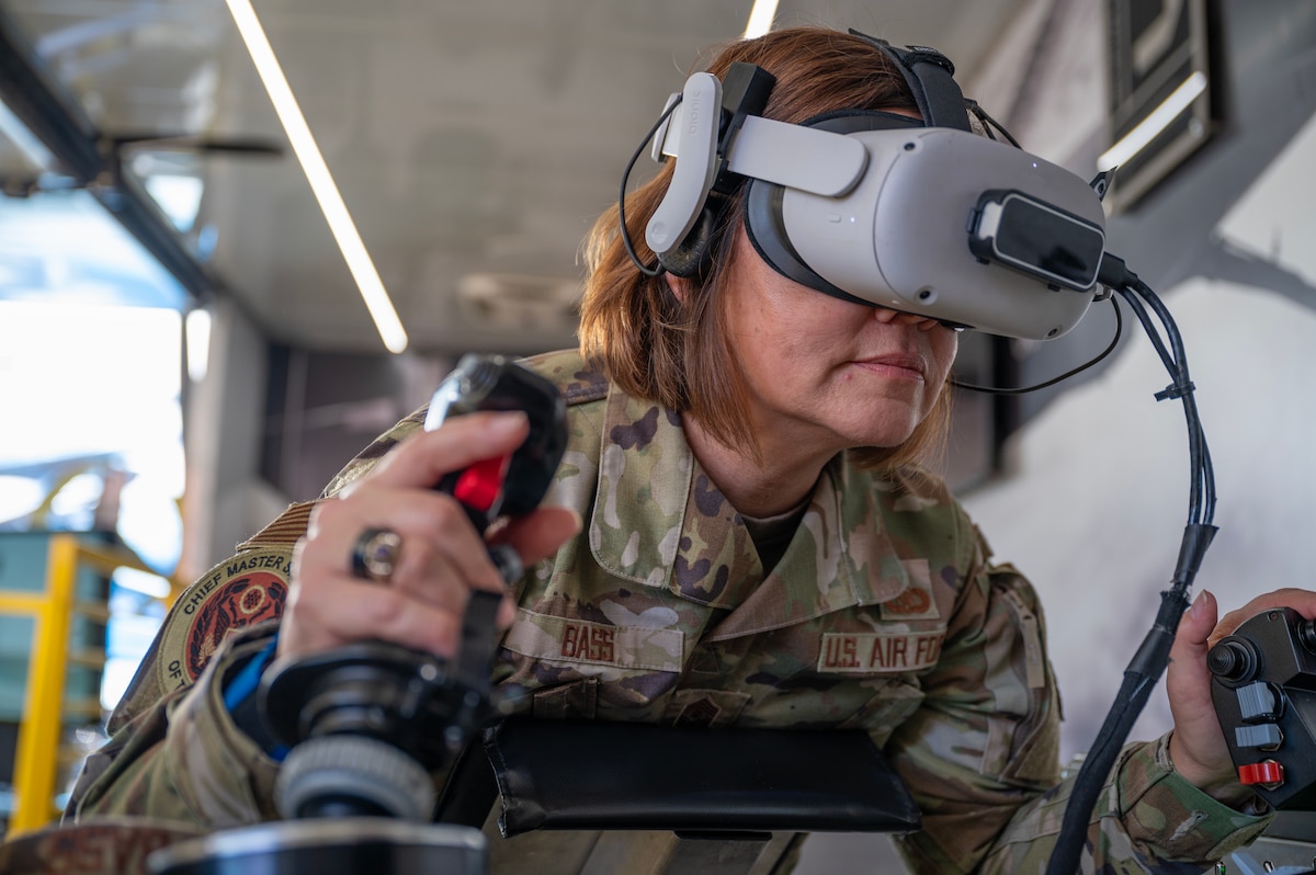 Chief Master Sgt. of the Air Force JoAnne S. Bass operates a virtual reality in-flight refueling simulation at the U.S. Air Force recruiting booth supporting a Formula Drift event at the Irwindale Speedway in Irwindale, CA, Oct. 14, 2023. The VR recruiting asset allows the public to challenge themselves by virtually operating a simulated aerial refueling boom, giving fuel to three different aircraft in a short amount of time. (U.S. Air Force photo by Staff Sgt. Colin Hollowell)