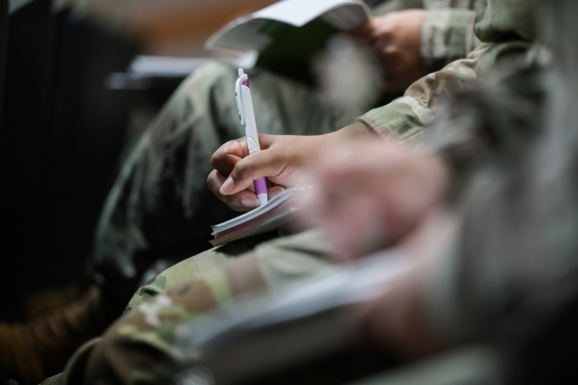 Airmen write notes during a brief at an additional duty first sergeant symposium at Joint Base Pearl Harbor-Hickam, Hawaii, Oct. 16, 2023. Airmen and Guardian noncommissioned officers from 12 supporting agencies on Oahu are attending the symposium to prepare for their future roles as additional duty first sergeants. (U.S. Air Force photo by Staff Sgt. Alan Ricker)