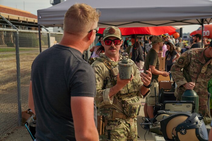 U.S. Air Force Staff Sgt. Connor Ely, Explosive Ordnance Disposal (EOD) technician, 9th Civil Engineer Squadron, explains the components of a Bouncing Betty anti-personnel landmine to a community member at the Chico Regional Airport Open House in Chico, California on Oct. 14, 2023.
