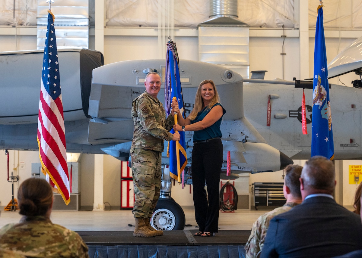 U.S. Air Force Col. John Creel, 12th Air Force (Air Forces Southern) deputy commander, presents a guidon to Linda Morales, CEO of The Planning Center, signifying her status as 12th AF honorary commander at Davis-Monthan Air Force Base, Ariz., Oct. 12, 2023. Morales had a role in the Tucson community and was a part of the DM50 organization which aimed to make the lives of Airmen at DM better.