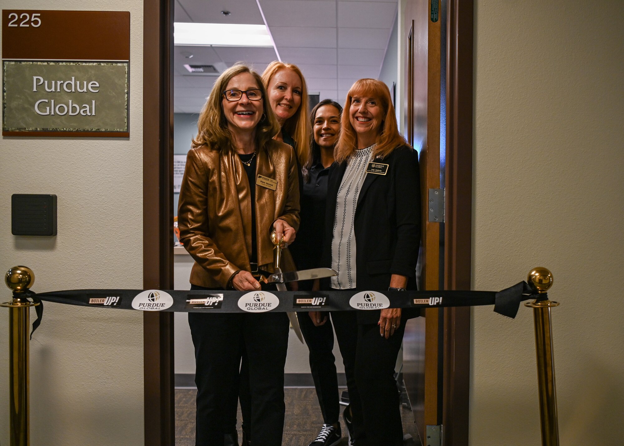 A college vice president, associate vice president and dean pose for a photo as they prepare to cut a ribbon during an education center open house.