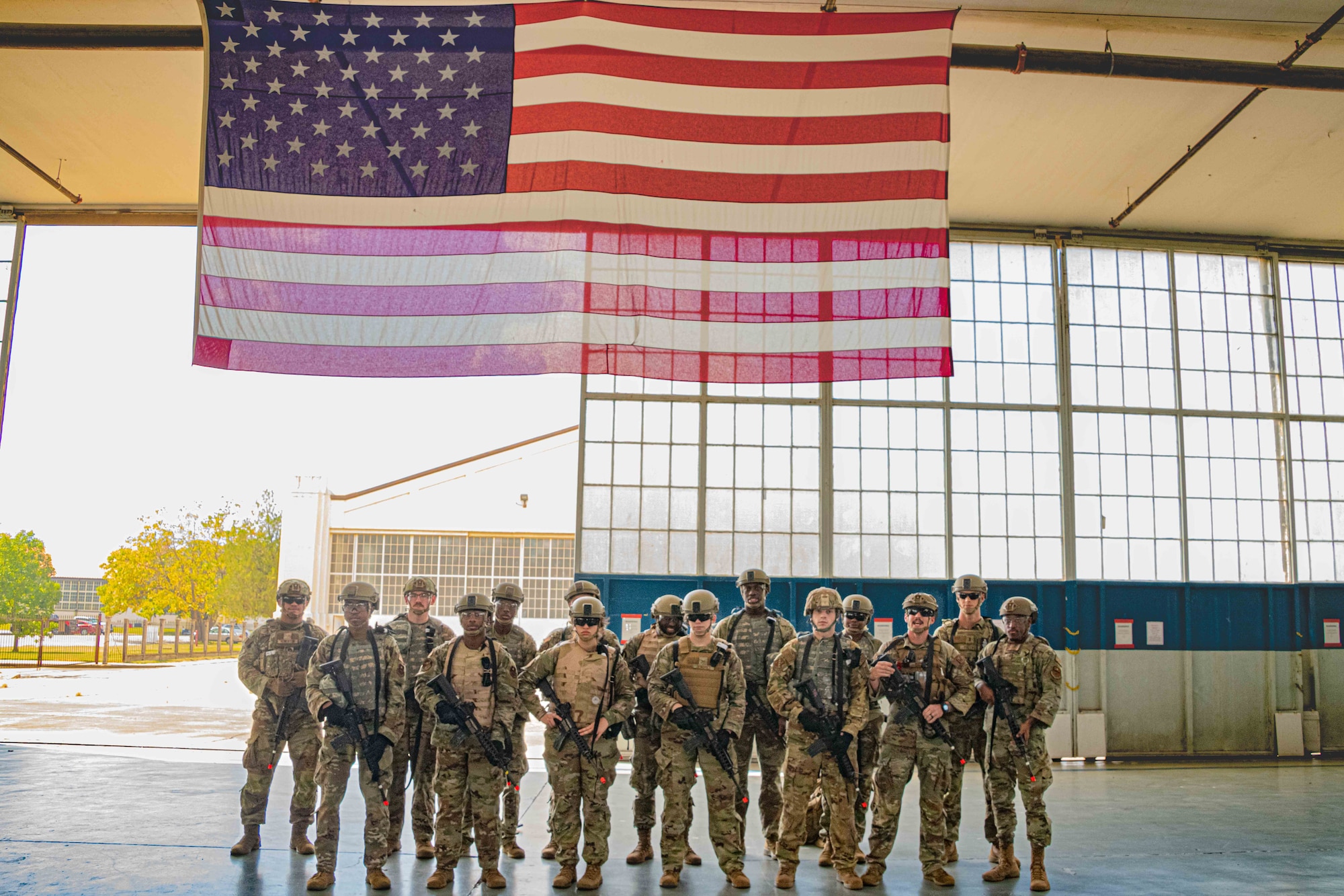Military members standing in a hanger under the American flag