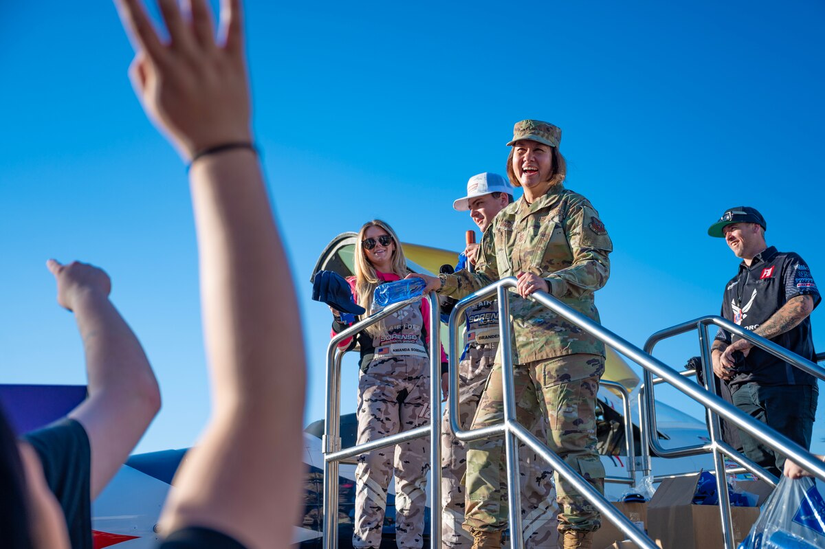 Chief Master Sgt. of the Air Force JoAnne S. Bass joins Branden and Amanda Sorensen, Air Force Recruiting Service-sponsored drivers, to pass out U.S. Air Force recruiting merchandise to Sorensen Motorsports fans in front of the U.S. Air Force recruiting booth during a Formula Drift event at the Irwindale Speedway in Irwindale, CA, Oct. 14, 2023. A crowd gathered in front of the USAF Thunderbird F-16 Fighting Falcon where the Sorensen’s and CMSAF Bass distributed USAF recruiting merchandise to the fans. (U.S. Air Force photo by Staff Sgt. Colin Hollowell)