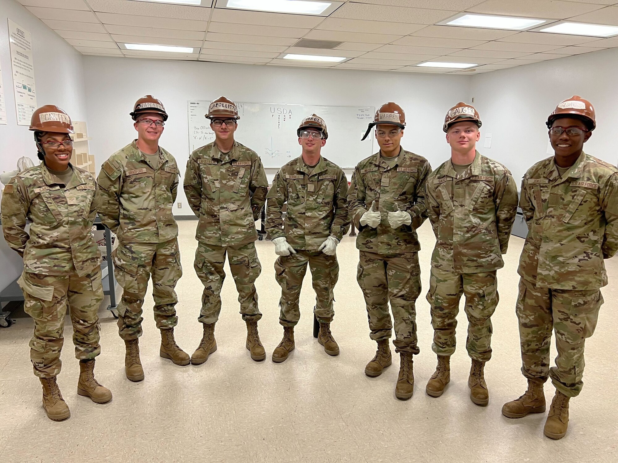 People in military uniforms wear hard hats and gloves