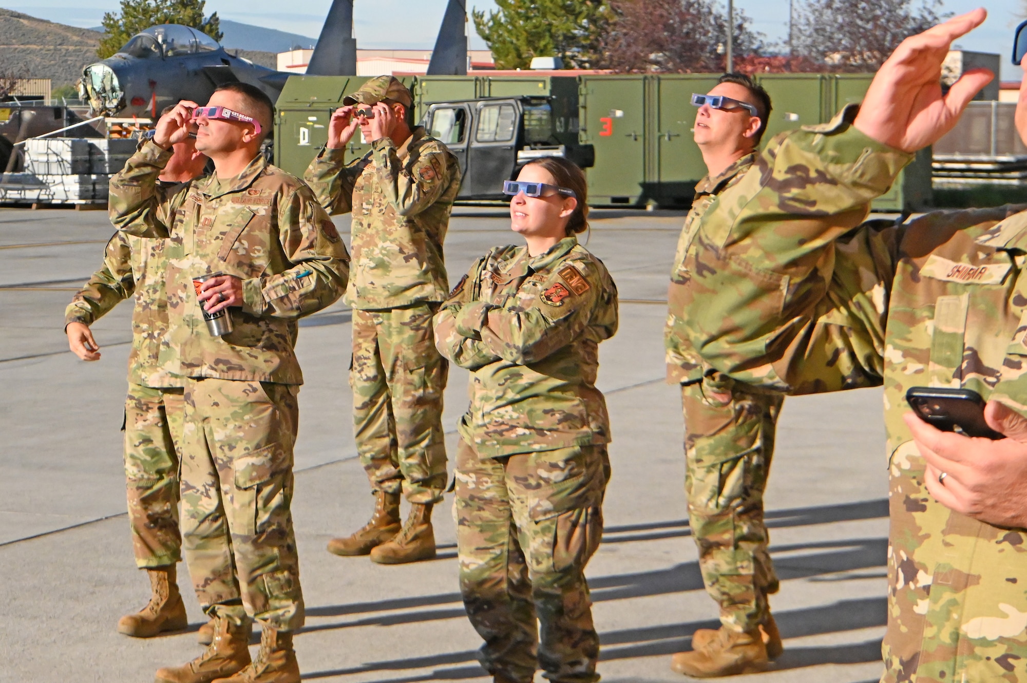 A group of 173rd Fighter Wing Airmen gather in front of the hanger to view the sun being covered by the moon.