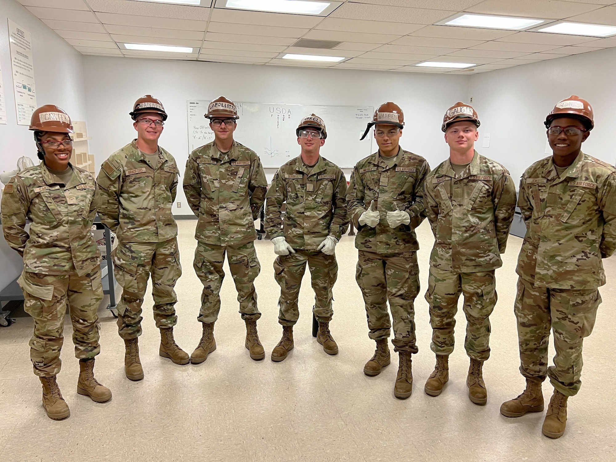People in military uniforms wear hard hats and gloves