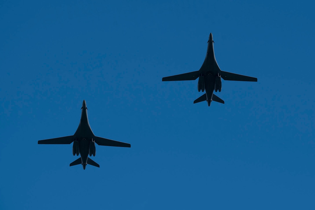 Two B-1B Lancers fly against a blue sky.