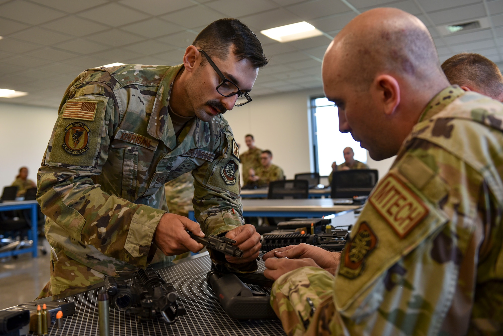 A Combat Arms Instructor assists an Airman in assembling and M4 Carbine rifle.