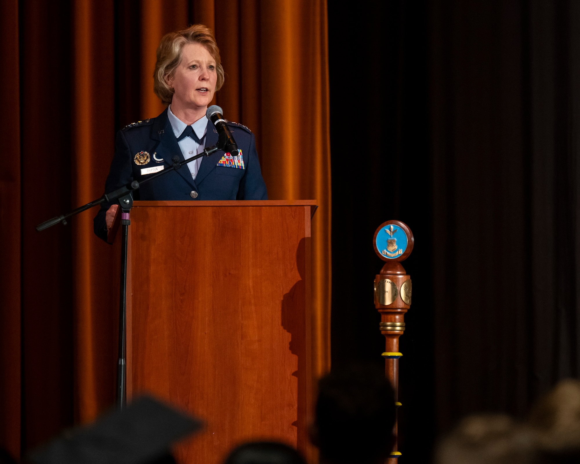 A woman in Air Force uniform stands behind a podium speaking.