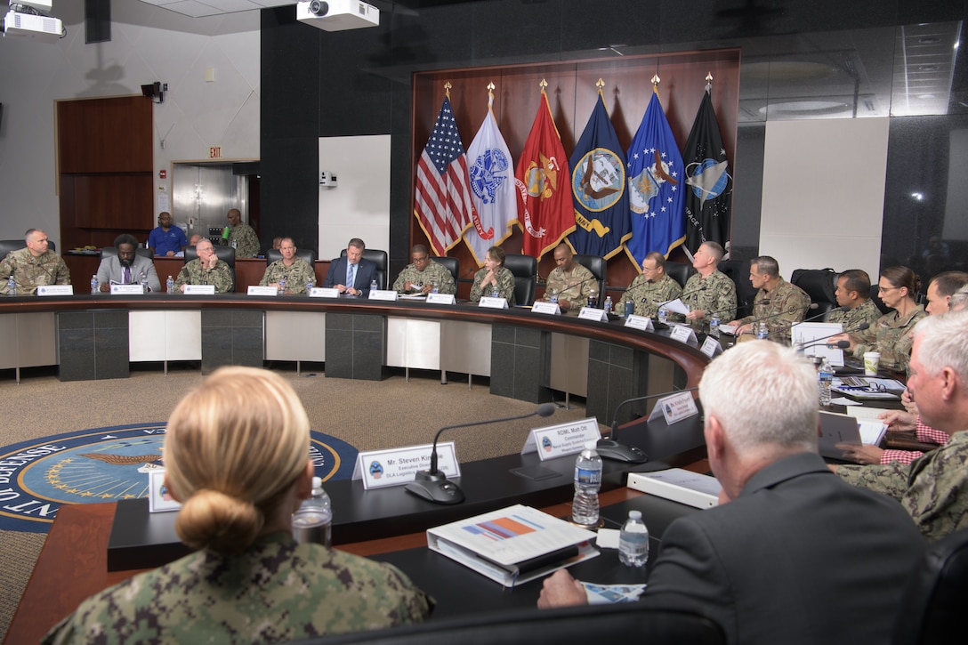 A group of Defense Logistics Agency and Navy leaders sit around a table in a conference room.