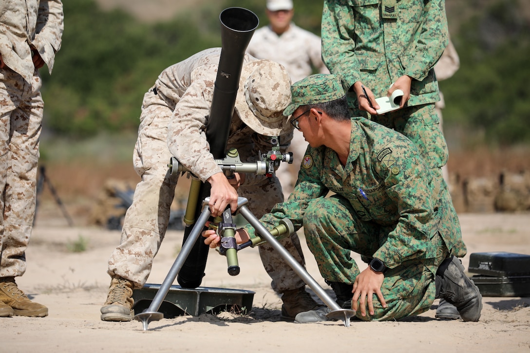 U.S. Marine Corps Lance Cpl. Gabriel Correia, left, with 2nd Battalion, 4th Marine Regiment, 1st Marine Division, and Singapore Guardsmen 3SG Kai Jie, a detachment commander with the 7th Singapore Infantry Brigade, conduct drills using a M252A2 81mm mortar system during a mortar subject matter expert exchange as part of Exercise Valiant Mark 2023 at Camp Pendleton, CA, Oct. 9, 2023. Valiant Mark 2023 is an annual, bilateral training exercise conducted between the Singapore Armed Forces and I Marine Expeditionary Force, designed to enhance interoperability, improve combined arms and amphibious warfighting skills, and strengthen military-to-military relationships. (U.S. Marine Corps photo by Sgt. Quince D. Bisard)