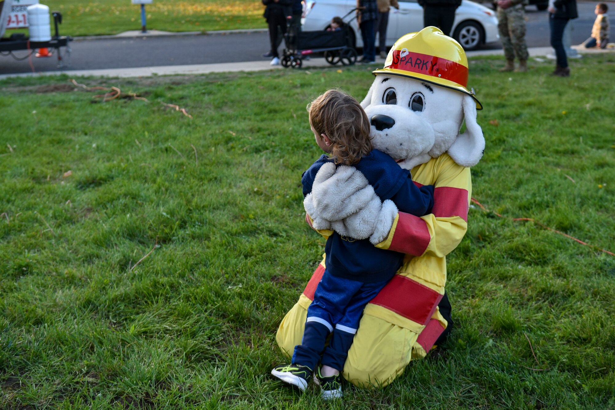 Sparky the Fire Dog hugs a child.