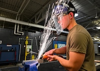 Airman 1st Class Houston Miller, 5th Maintenance Squadron aircraft structural maintenance (ASM) apprentice, grinds a titanium plate at Minot Air Force Base, North Dakota, Oct. 17, 2023. ASM specialists are responsible for performing repairs and maintaining the structural integrity of Team Minot’s fleet of B-52H Stratofortresses. (U.S. Air Force photo by Airman 1st Class Kyle Wilson)