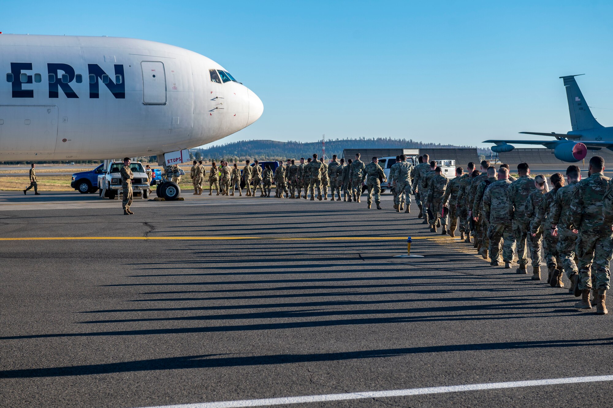 Airmen walk in a line to board a plane.