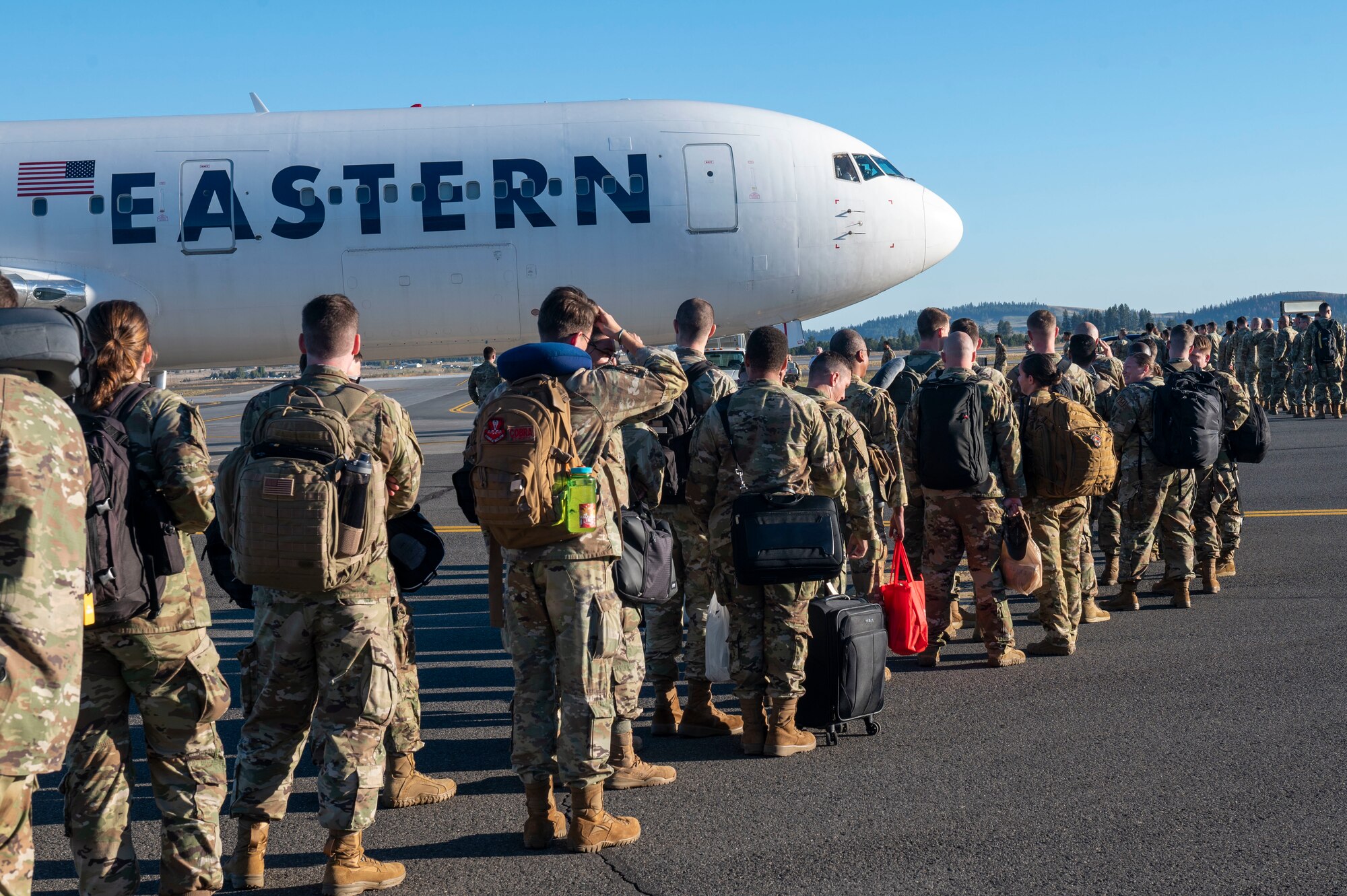 Airmen wait in line to board a plane.