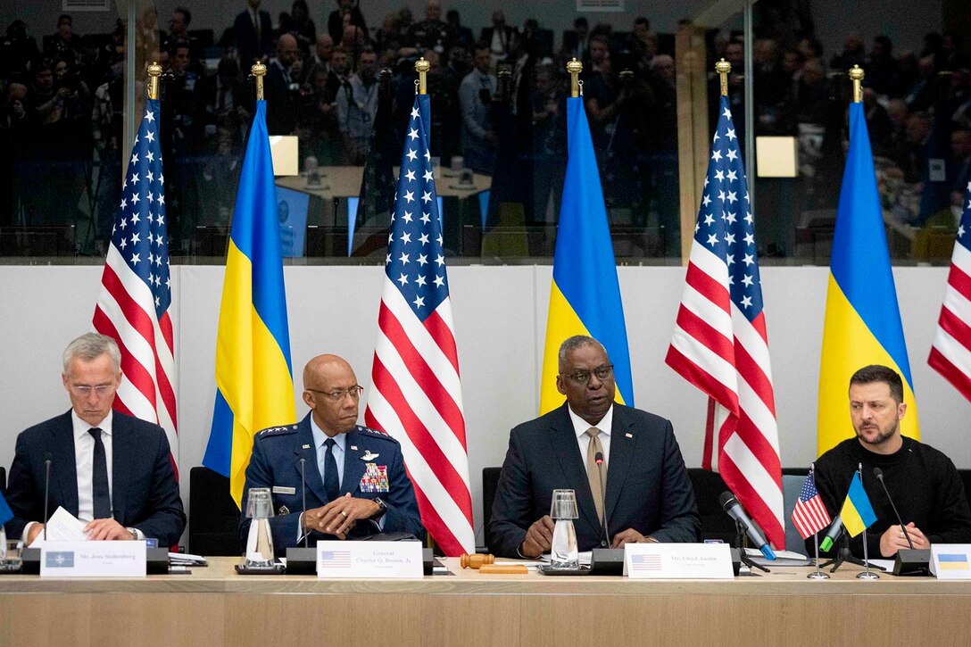 Four leaders sit next to one another at a long table in front of U.S. and Ukrainian flags.