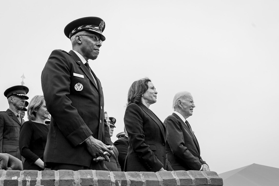 Air Force Gen. CQ Brown, Jr., President Biden and Vice President Harris stand in an outdoor seating area.