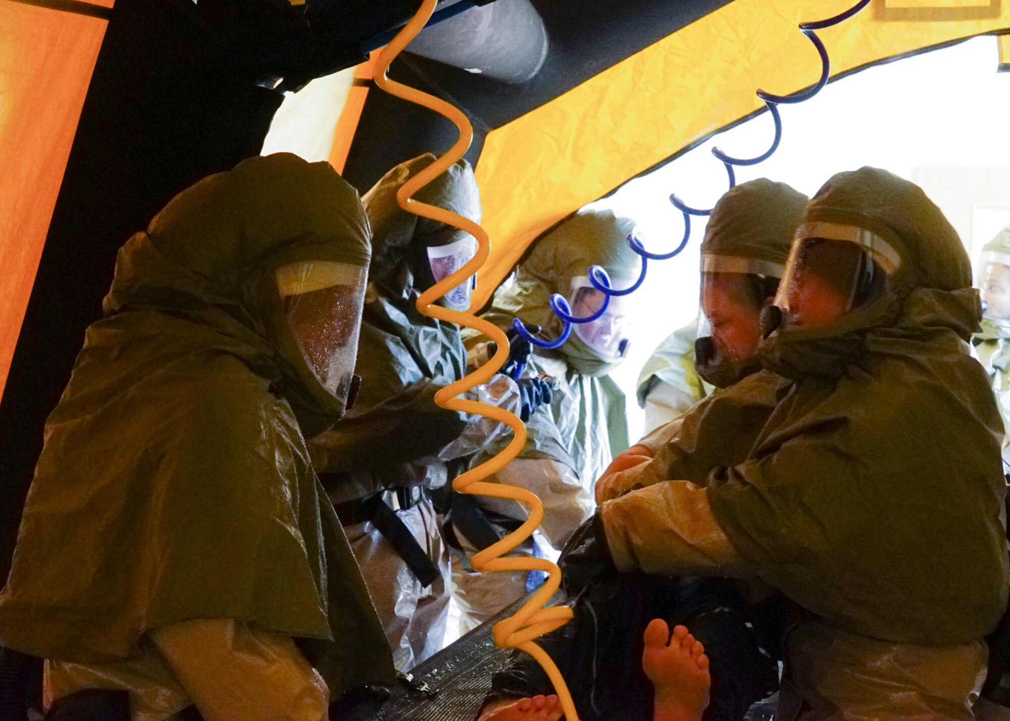 A group of Airmen decontaminate a volunteer patient.