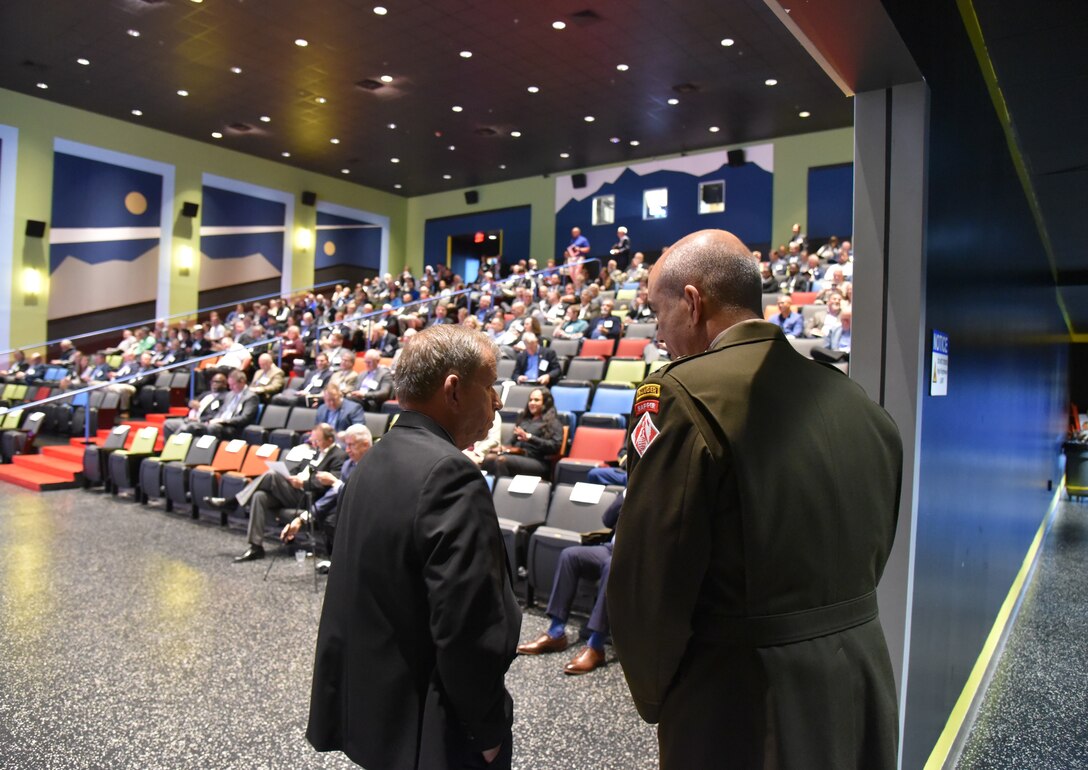 Col. Sebastien Joly, U.S. Army Engineering and Support Center Huntsville, and Albert “Chip” Marin III, Huntsville Center Programs and Business Director, standing in front of attendees in an auditorium during Industry Day and Small Business Forum 2023 at the Davidson Center for Space Exploration at the U.S. Space and Rocket Center in Huntsville, Ala., Oct. 18, 2023.