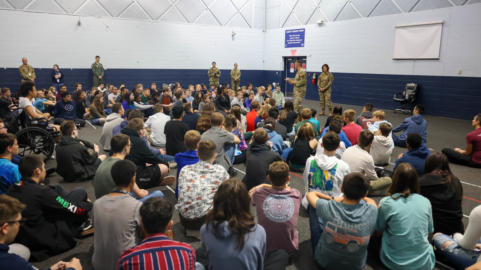 students listening to speaker in gym