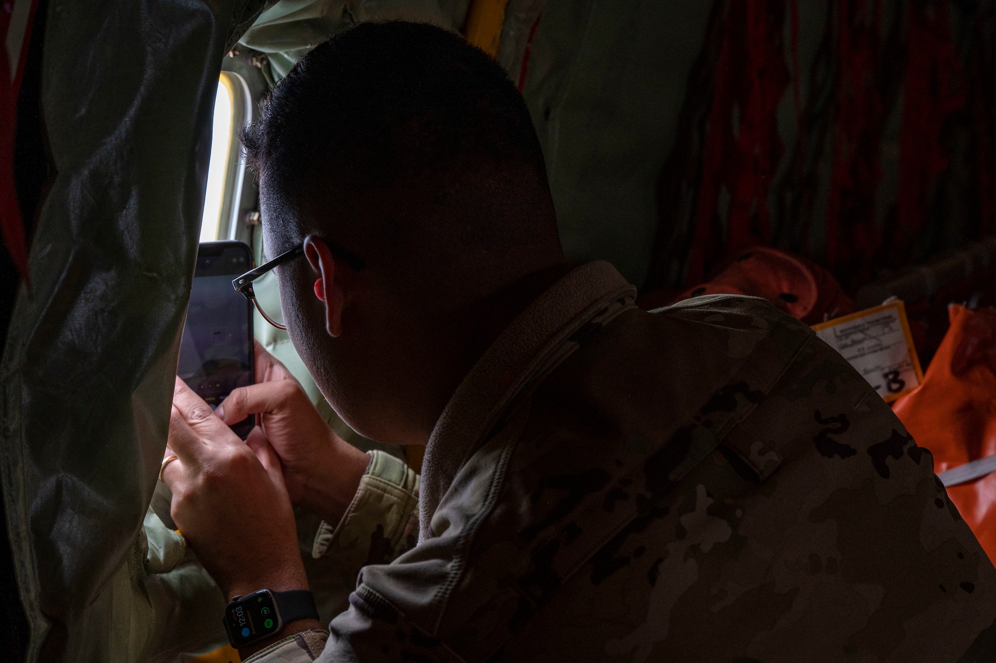 An Airman takes a photo with his cell phone of the sky through the window of a KC 135 Stratotanker.