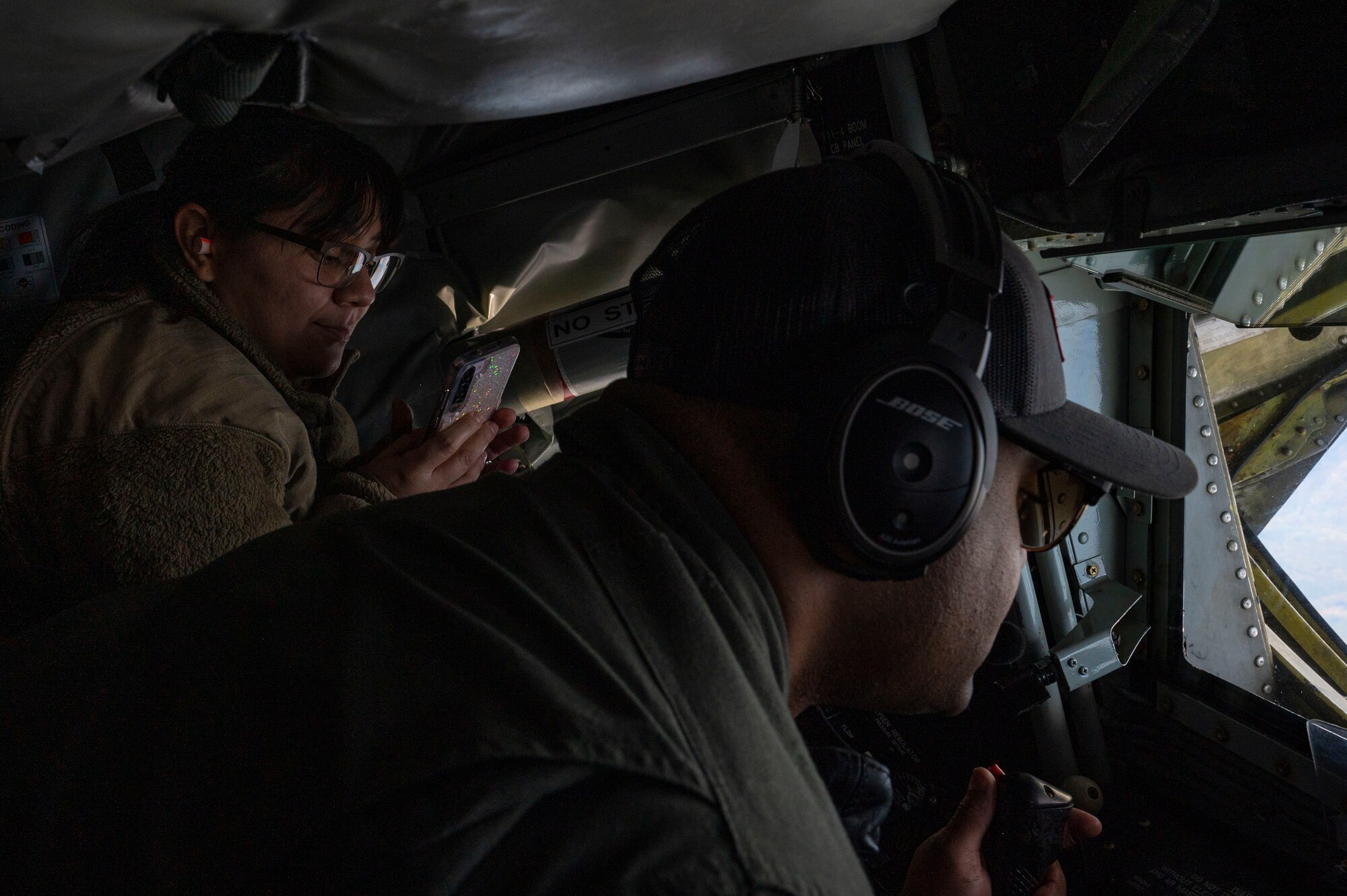 An Airman photographs aerial refueling on her cell phone.