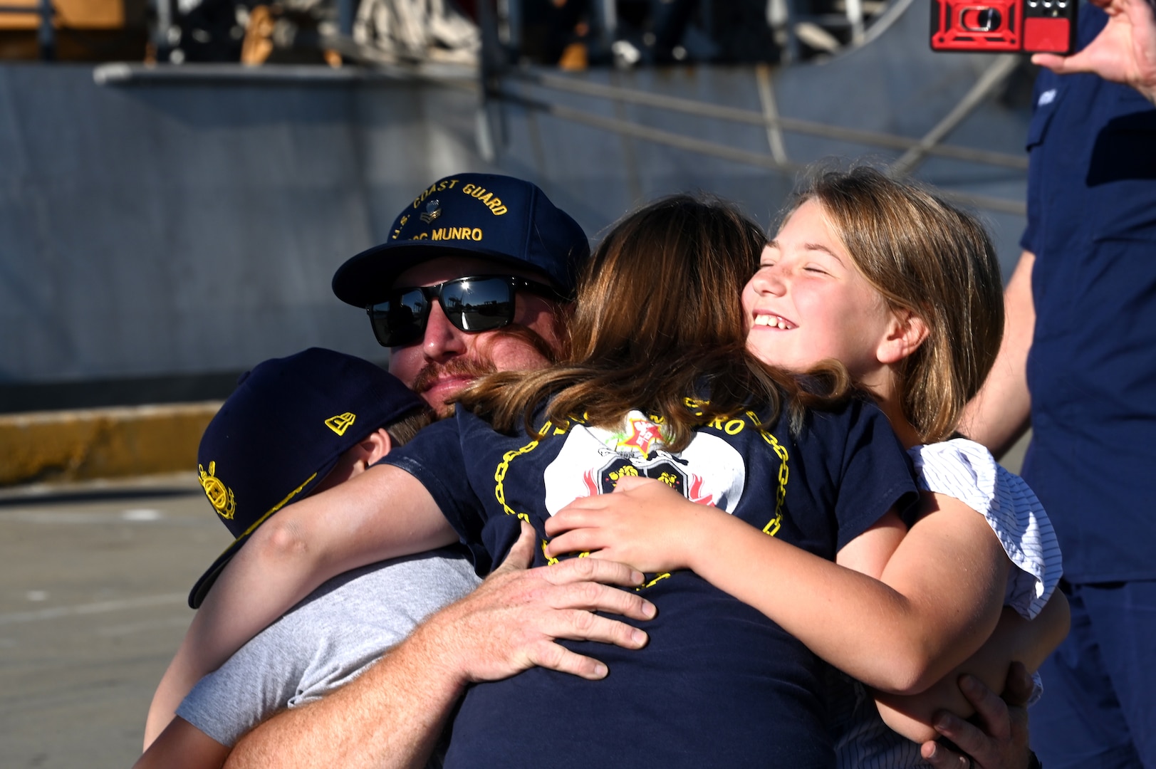 Petty Officer 1st Class Aundré Behnken, an information systems technician aboard the U.S. Coast Guard Cutter Munro (WSML 755), embraces his family on the pier at Base Alameda, California, after Munro returned home from a 118-day Western Pacific deployment, Oct. 18. 2023. Munro's crew conducted a 23,000-mile, multi-month Western Pacific patrol operating in support of the U.S. Navy's Seventh Fleet by conducting multiple engagements with partner nations promoting a free and open Indo-Pacific. U.S. Coast Guard photo by Chief Petty Officer Matthew S. Masaschi.