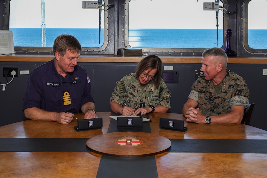 ATLANTIC OCEAN (Oct. 18, 2023) – Vice Chief of Naval Operations Adm. Lisa Franchetti (center), Commandant of the Marine Corps Gen. Eric Smith (right), and Royal Navy First Sea Lord and Chief of Naval Staff Adm. Sir Ben Key (left) sign a Delivering Combined Seapower (DCS) charter, which is intended to achieve the Service Chiefs’ combined vision for US-UK interoperability moving toward interchangeability, while visiting the HMS Prince of Wales (R09), Oct. 18. (U.S. Marine Corps photo by Sgt. Rachaelanne Woodward)