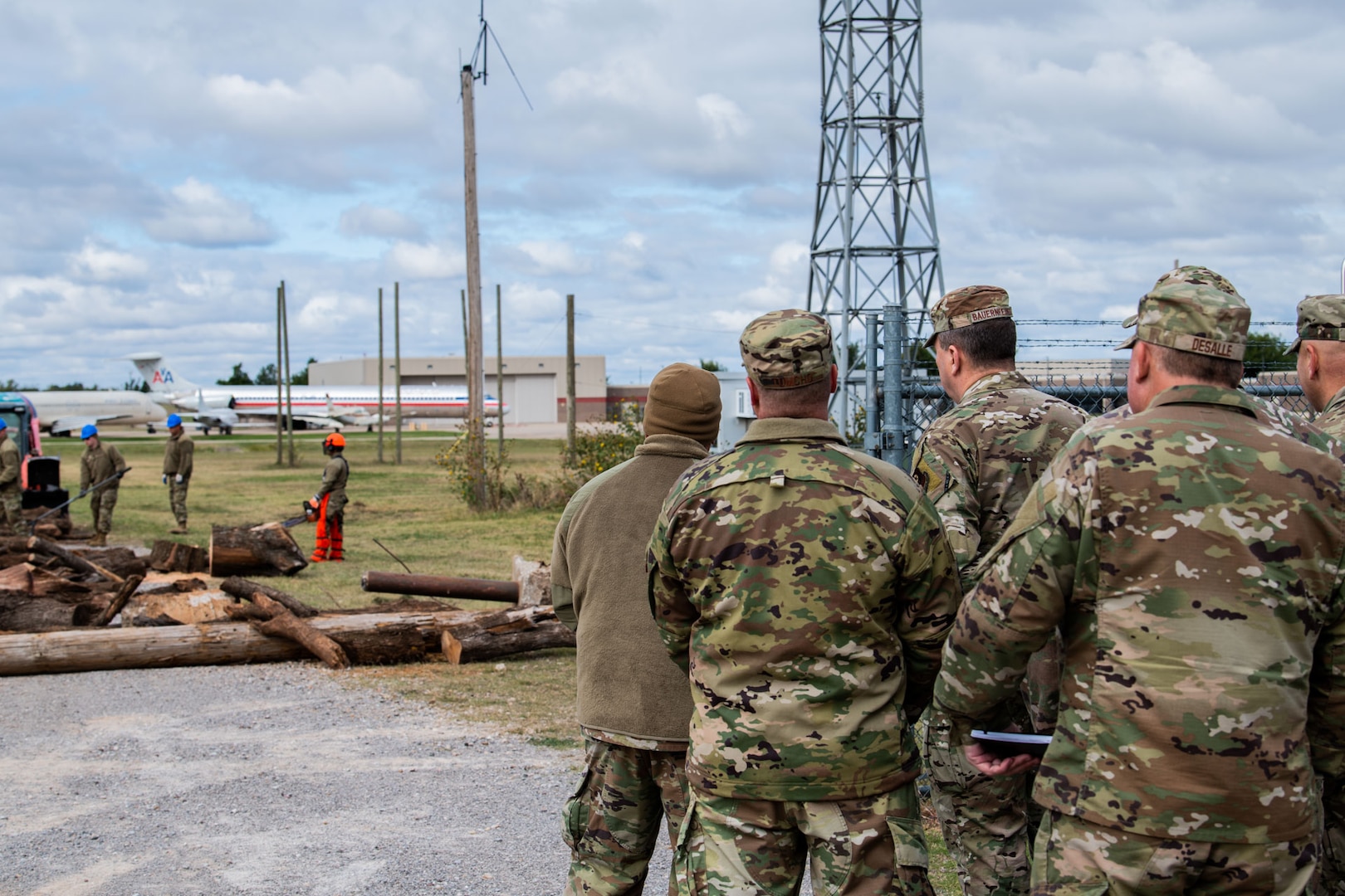Airmen observe a group of people clearing debris during training