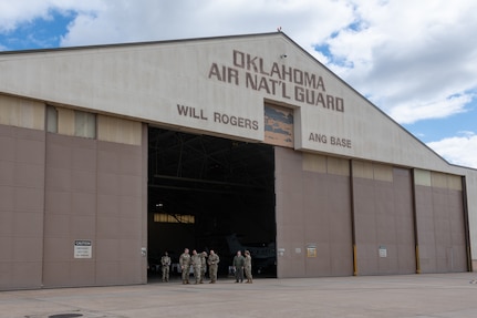 Airmen stand in front of a hangar