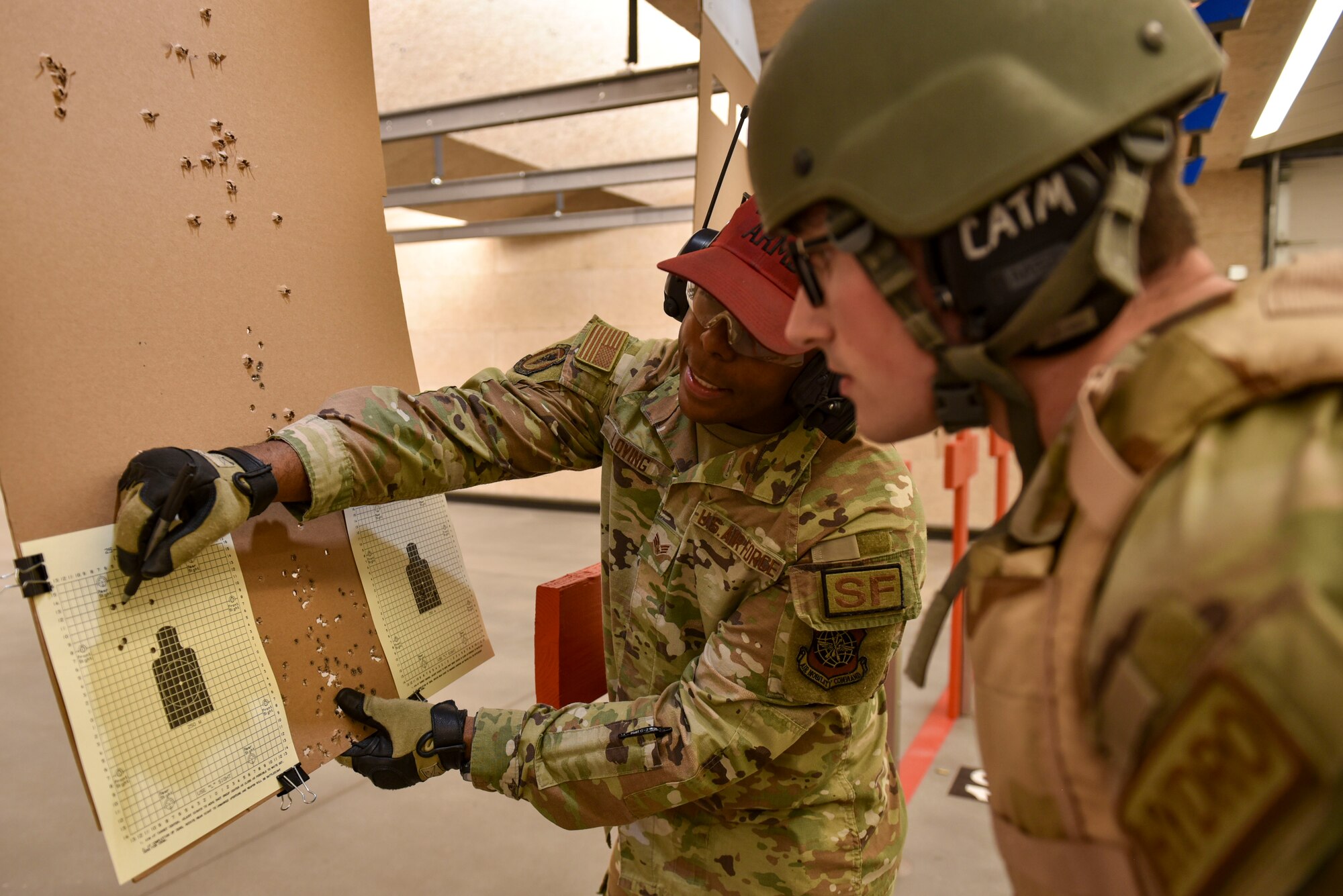 A Combat Arms Instructor reviews a firing target with another Airman.