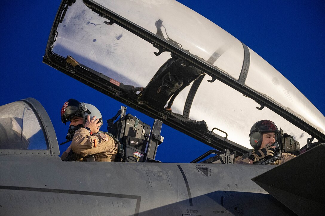 Two airmen make adjustment prior to takeoff.