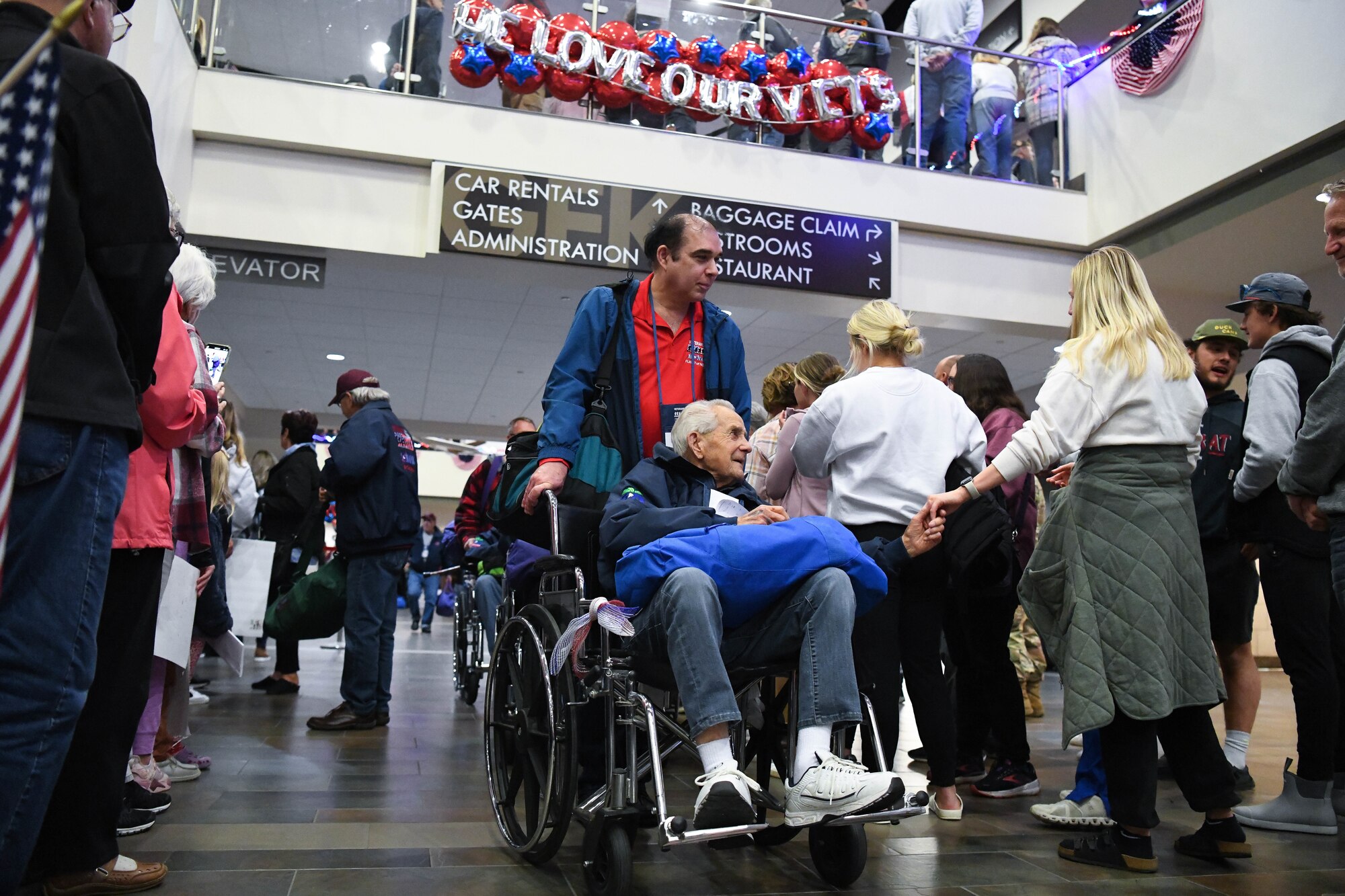 Veteran in wheelchair shakes hands with members of the crowd while in an airport.