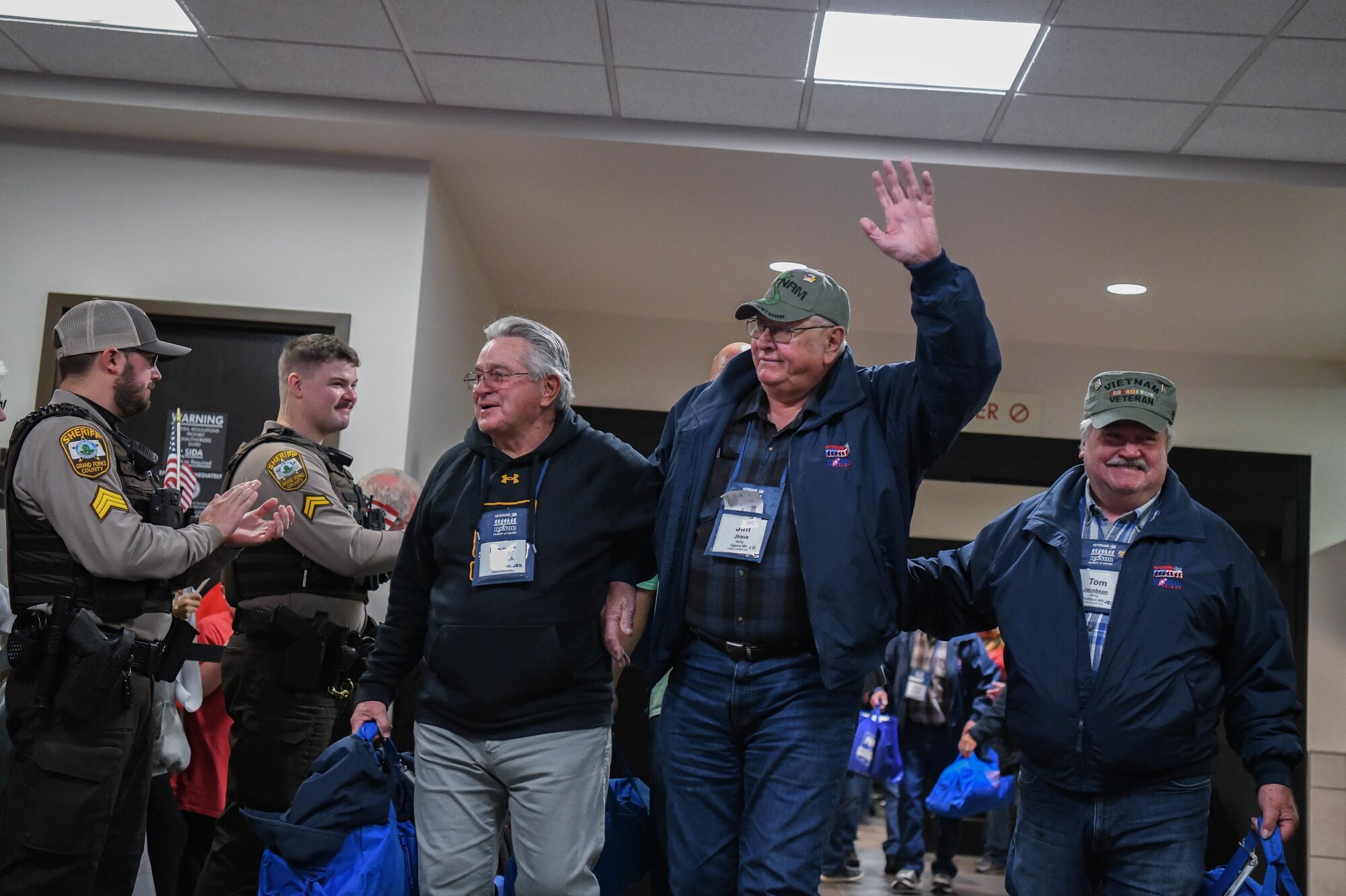 Three veterans wave as they walk through an airport.
