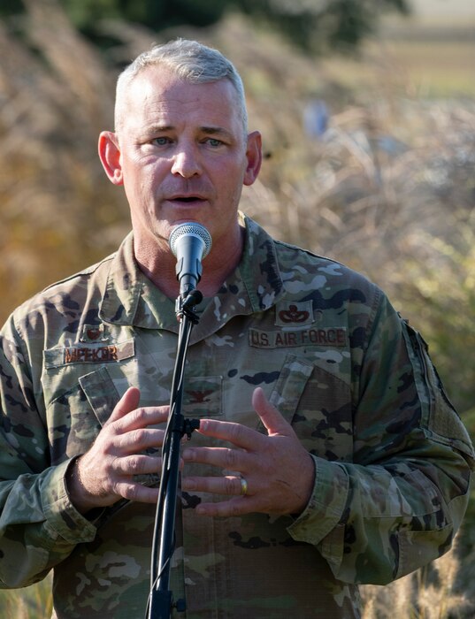 A man in Air Force camouflage speaks into a microphone.