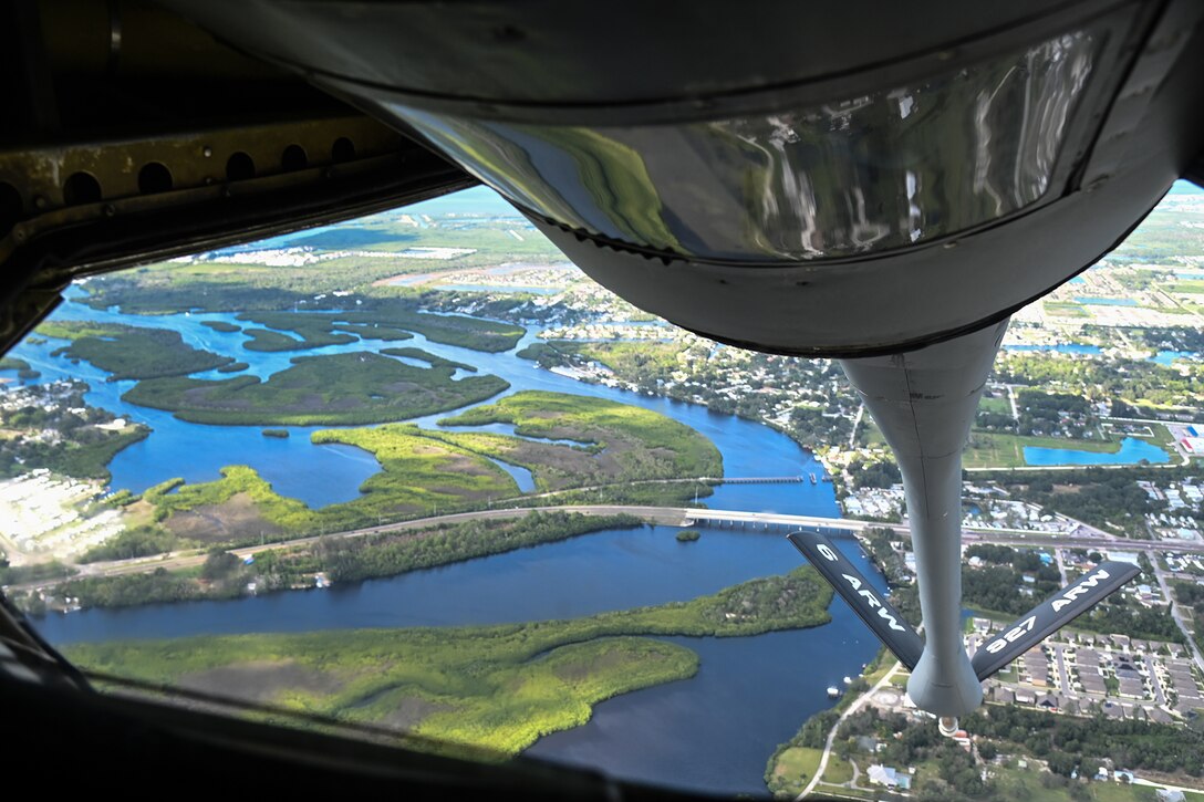 An aerial view of waterways, land and homes can be seen from the underside of a military aircraft.