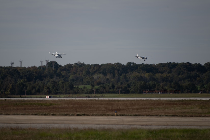 Two aircraft flying low, right about to land on a runway.