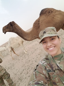 Woman in Army uniform poses for a selfie with a dromedary camel