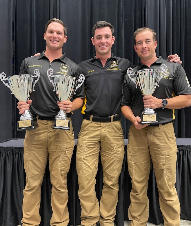 Three men in Army polos pose with three silver trophies