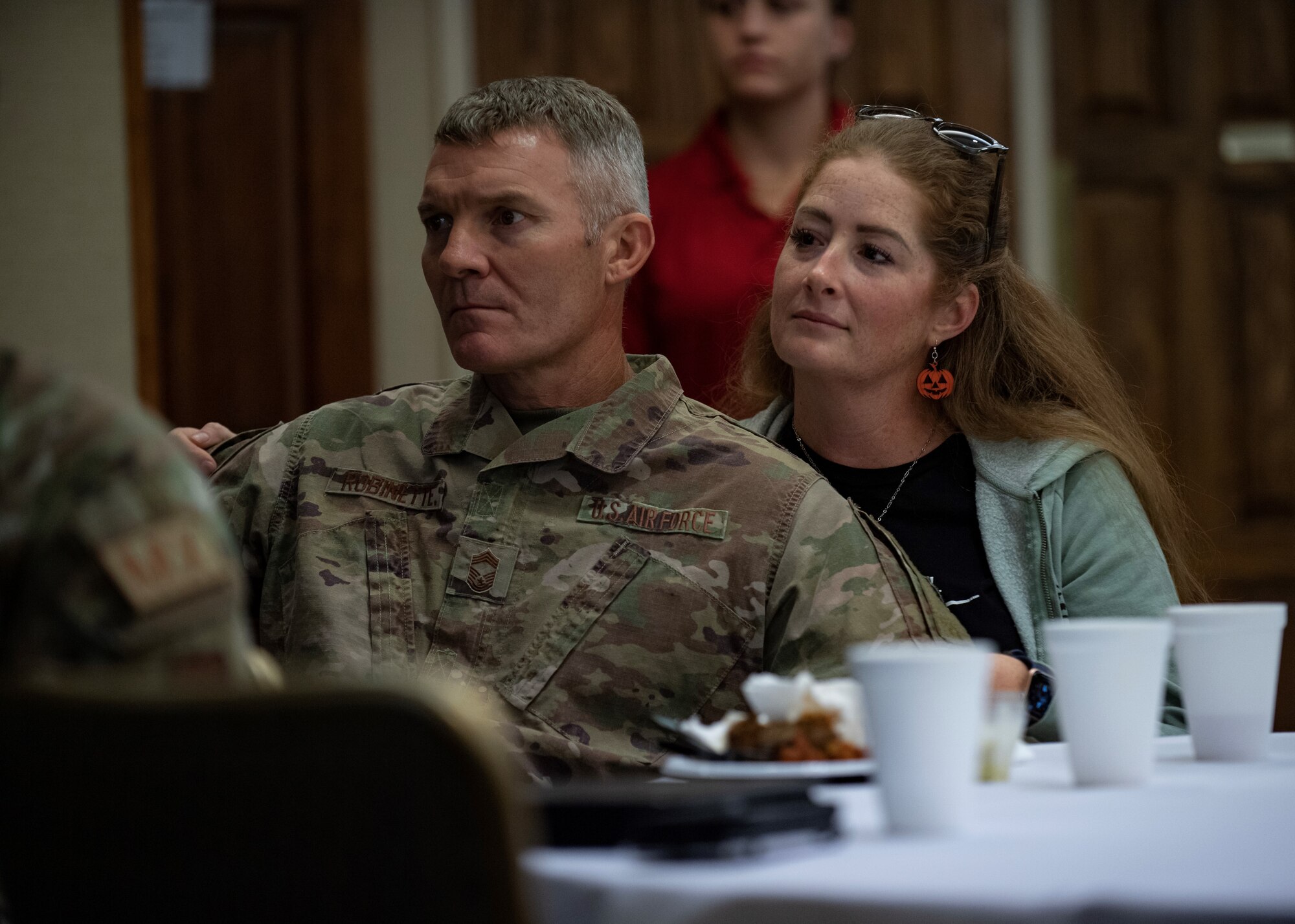 An Airman and his spouse watch a briefing