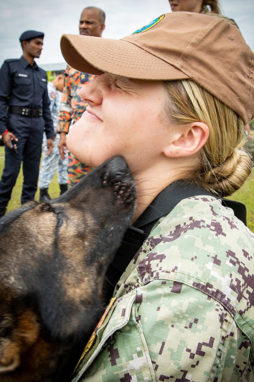 A dog gives a sailor kisses.