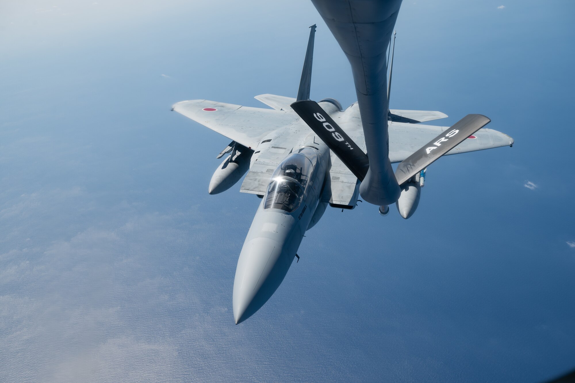 An aircraft approaches an aerial refueling boom.