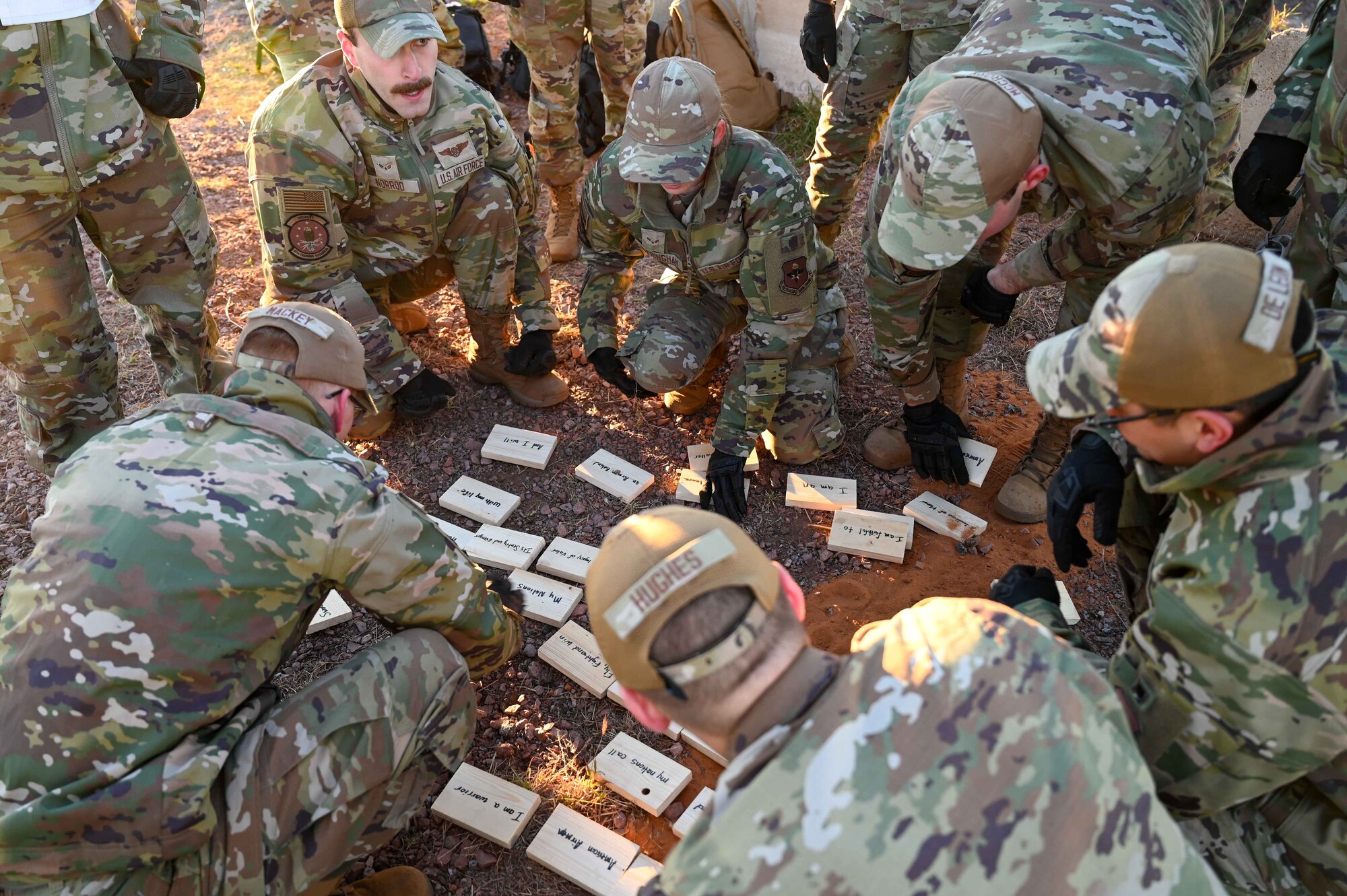 Students from the 97th Training Squadron huddle together to place phrases from the Airman’s Creed in the correct order during the Talon Challenge at Altus Air Force Base, Oklahoma, Oct. 14, 2023. At this exercise, students were tasked with carrying blocks with phrases from the Airman’s Creed up a hill and assembling them in order, ultimately leading to their recital of the creed as a team. (U.S. Air Force photo by Airman 1st Class Kari Degraffenreed)