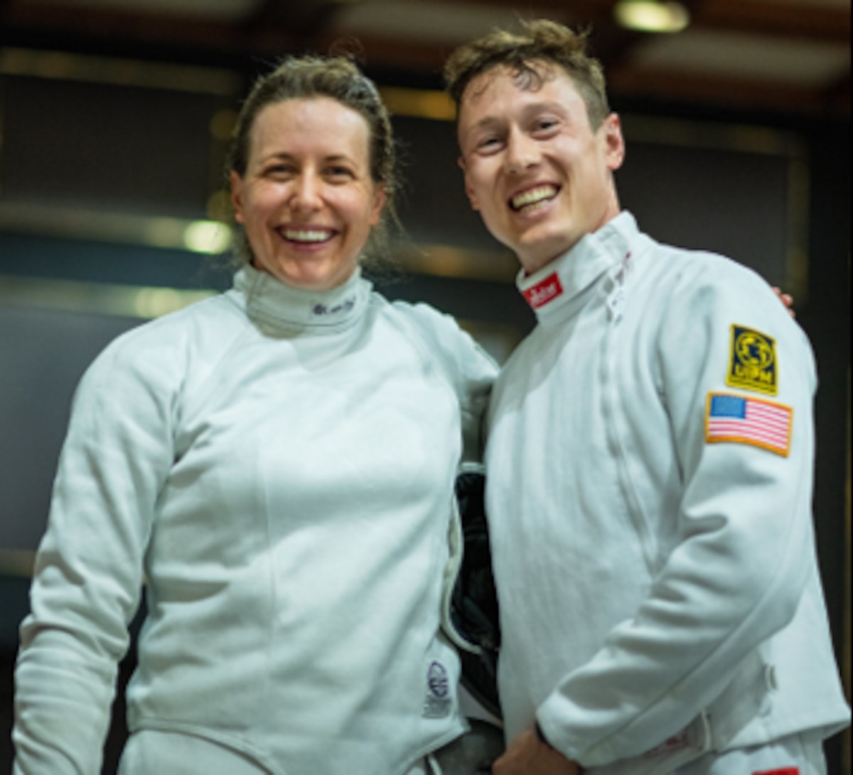 photo of athletes in fencing gear smiling at the camera