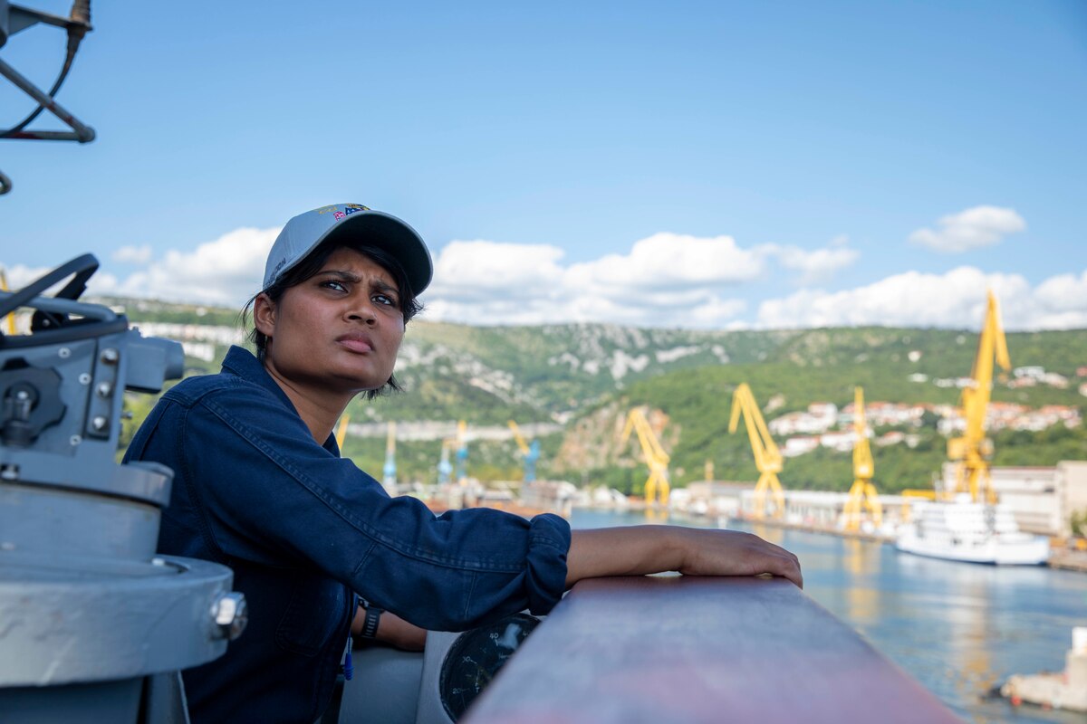 A sailor looks into the distance from a ship.