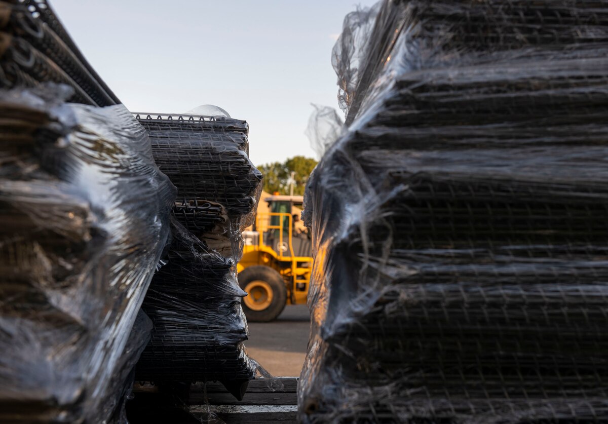 An Airman drives a forklift past an 18-wheeler.